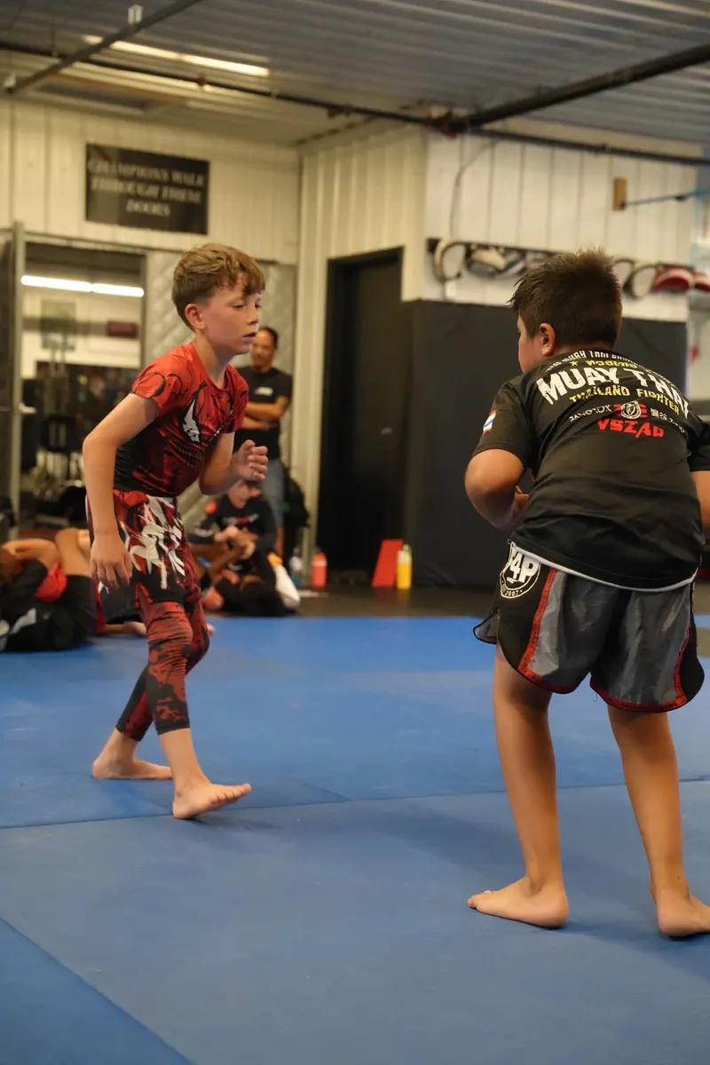 Two young jiu-jitsu students facing off in a stand-up exchange
